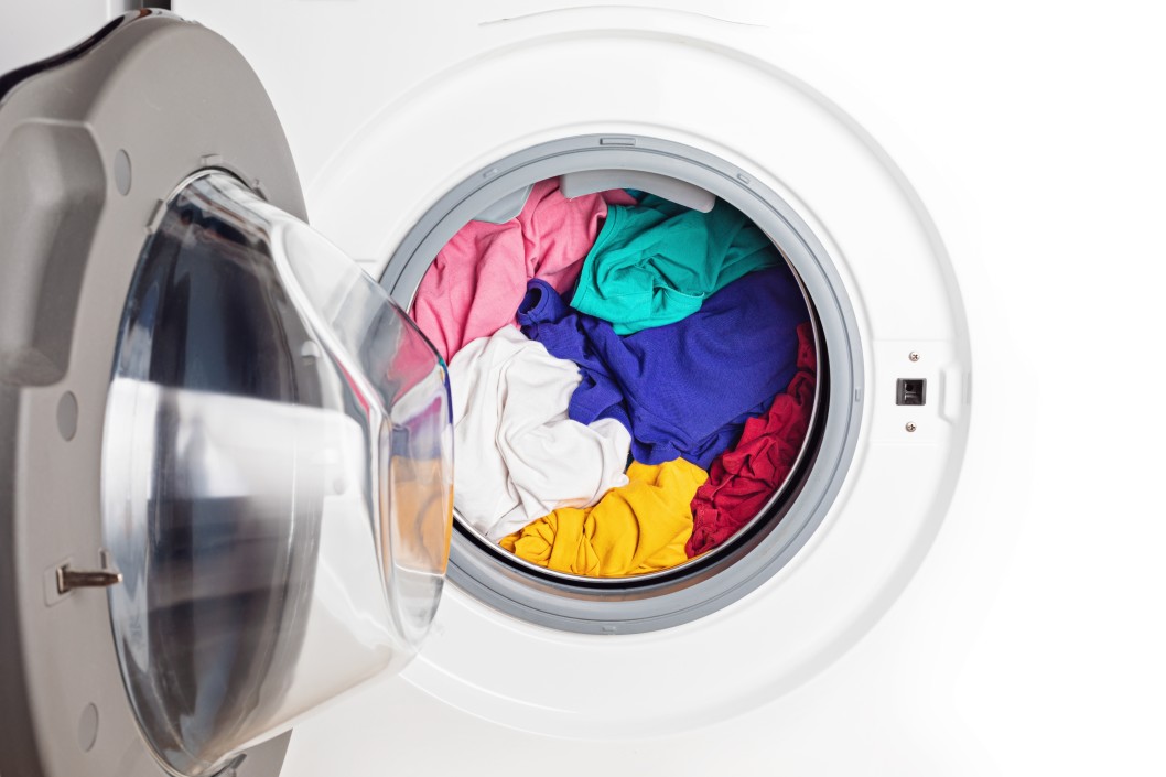 Open washing machine loaded with colorful laundry.